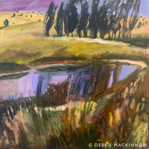 An abstract purple lake surrounded by brown green grasses and shrubs with dark green trees in a row in the distance and purple sky above