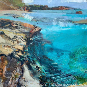 Jagged orange yellow rocks leaning over a bright turquoise and green ocean