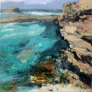 Turquoise and white sea with sand coloured jagged rocks next to it