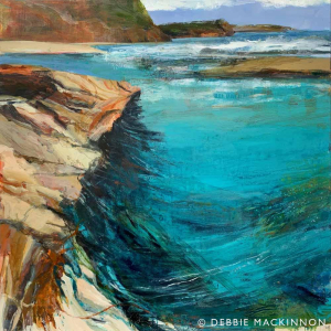 Jagged orange yellow rocks leaning over a bright turquoise and green ocean