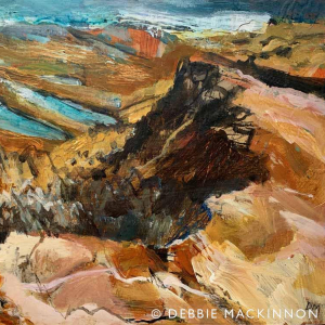 Colourful orange and pink rocks with jagged edges reaching out into a turquoise sea